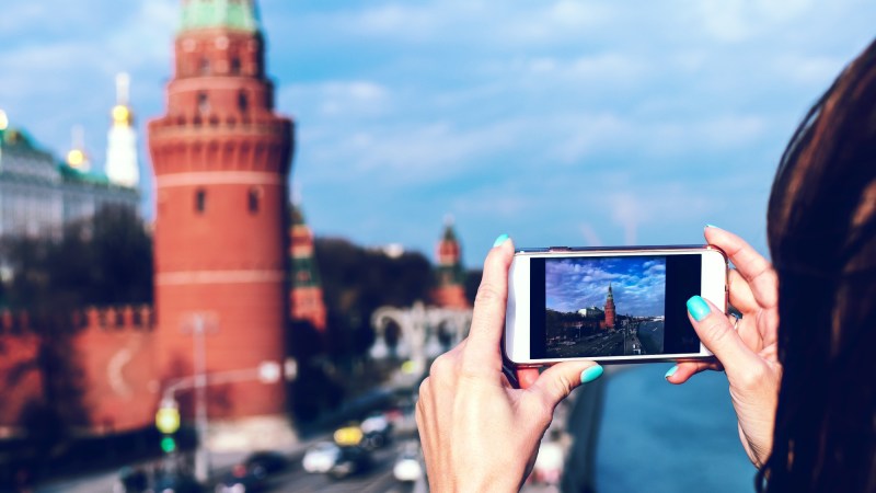 A person using an iPhone to take a photo of a brick building.