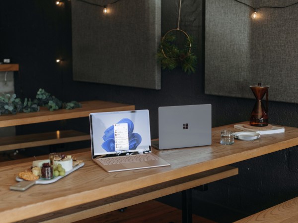 A Windows laptop left open next to another Windows device on a wooden table.