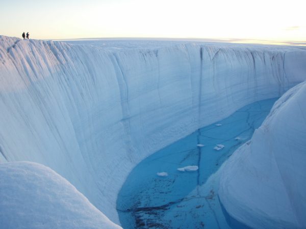 a large ice canyon with deep blue melted water in the middle