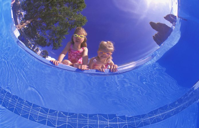 two kids stare down into a pool