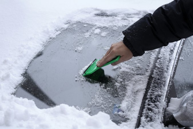 scraping ice and snow off a car windshield