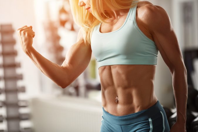 a blond woman with lots of muscles flexes for the camera 