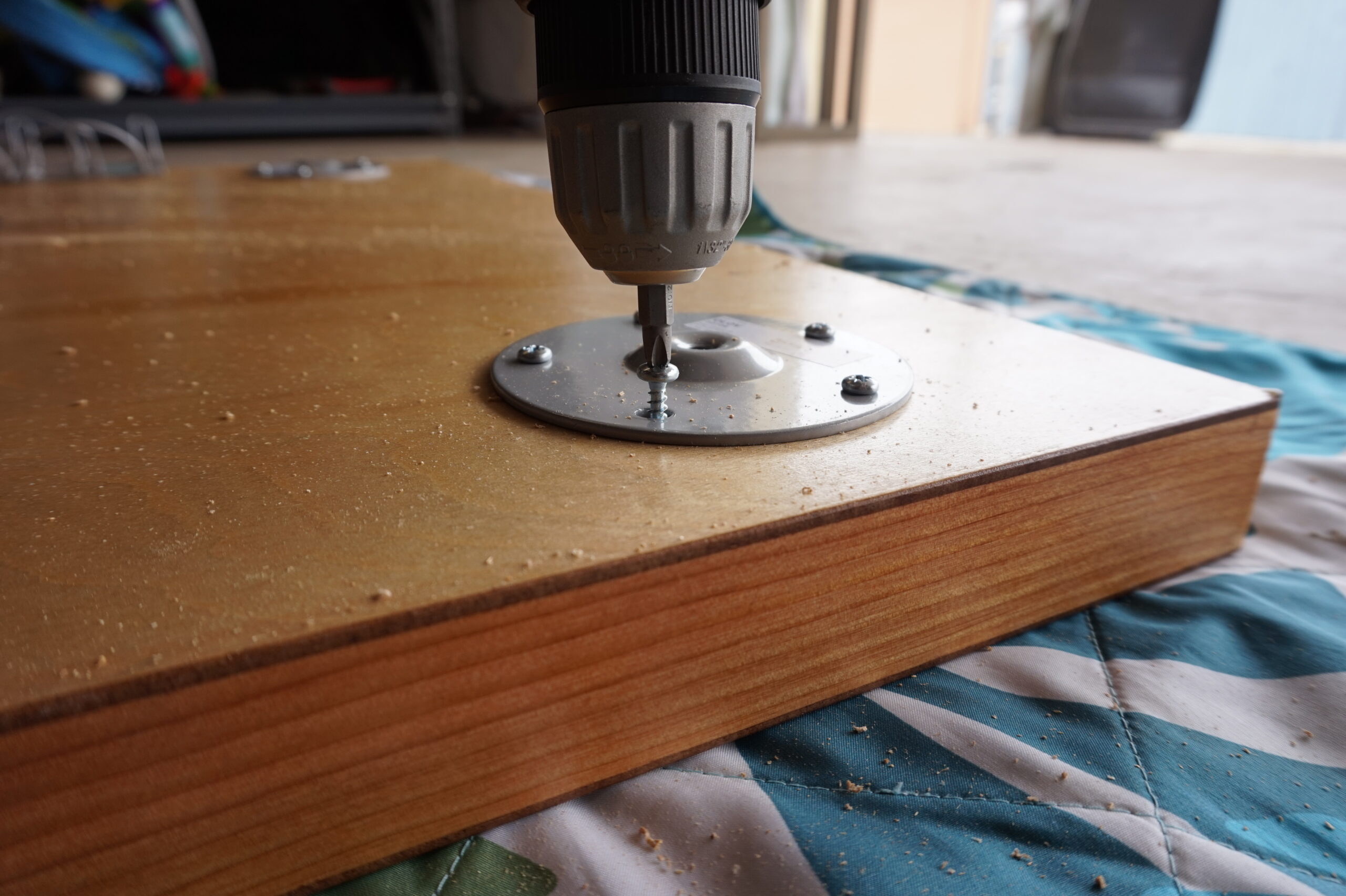 A person drilling legs onto the main part of a DIY computer desk.