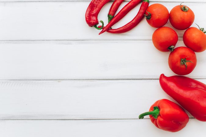 tomatoes and red peppers on a white table 