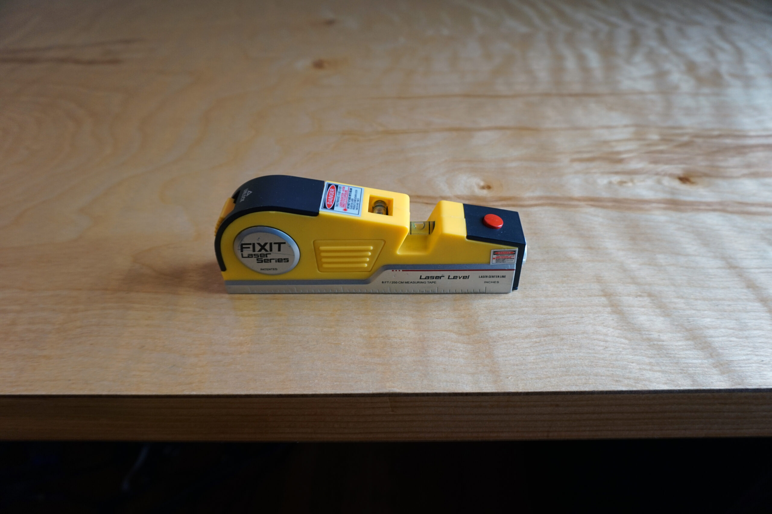 A small yellow level checking the top of a DIY computer desk for alignment.