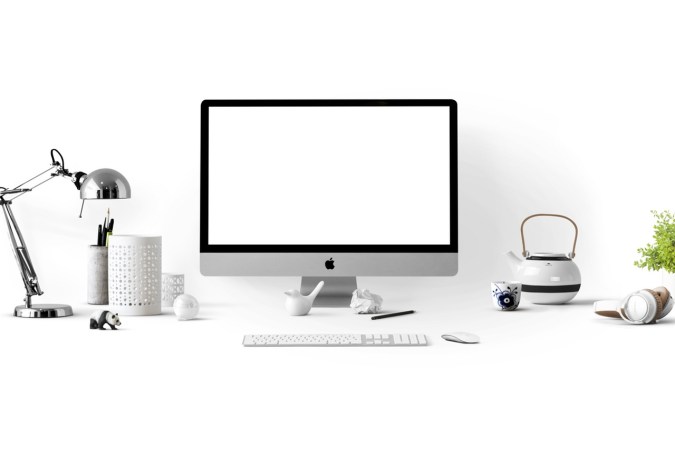 An Apple macOS computer on a white desk against a white background.