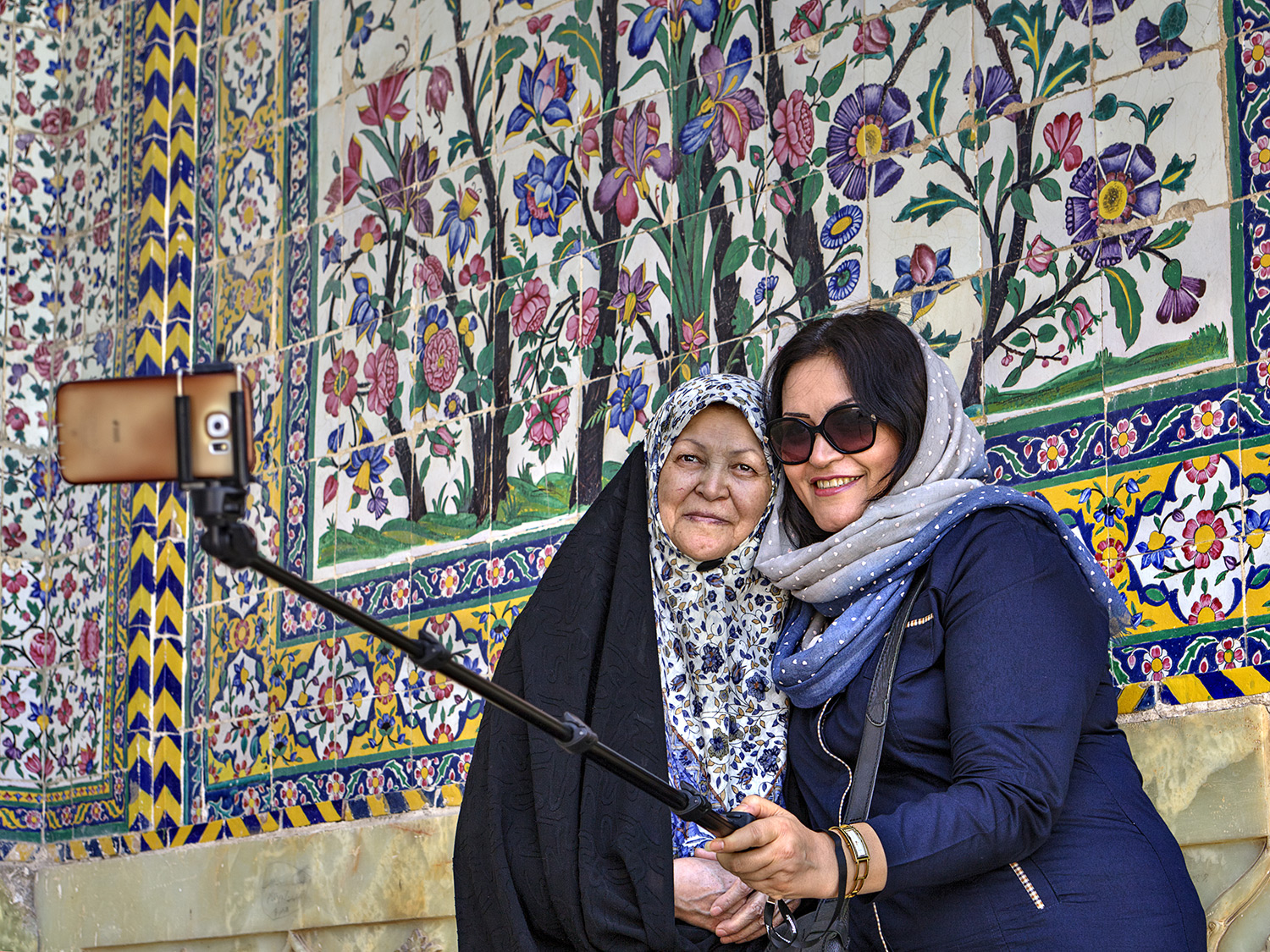 women taking pictures in front of mosaic