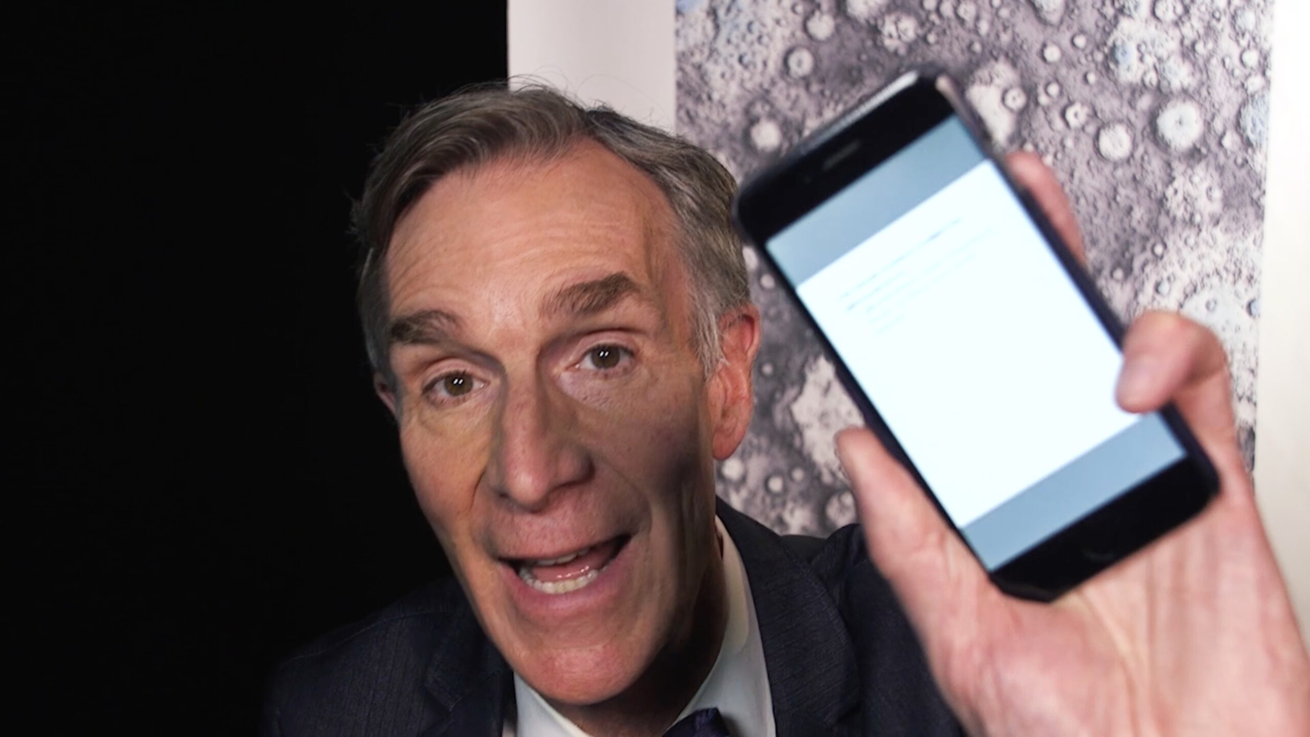 Bill Nye holding a phone