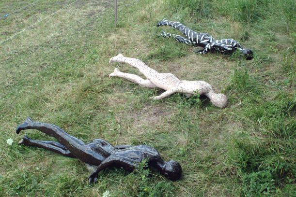 three mannequins lying face down in a field