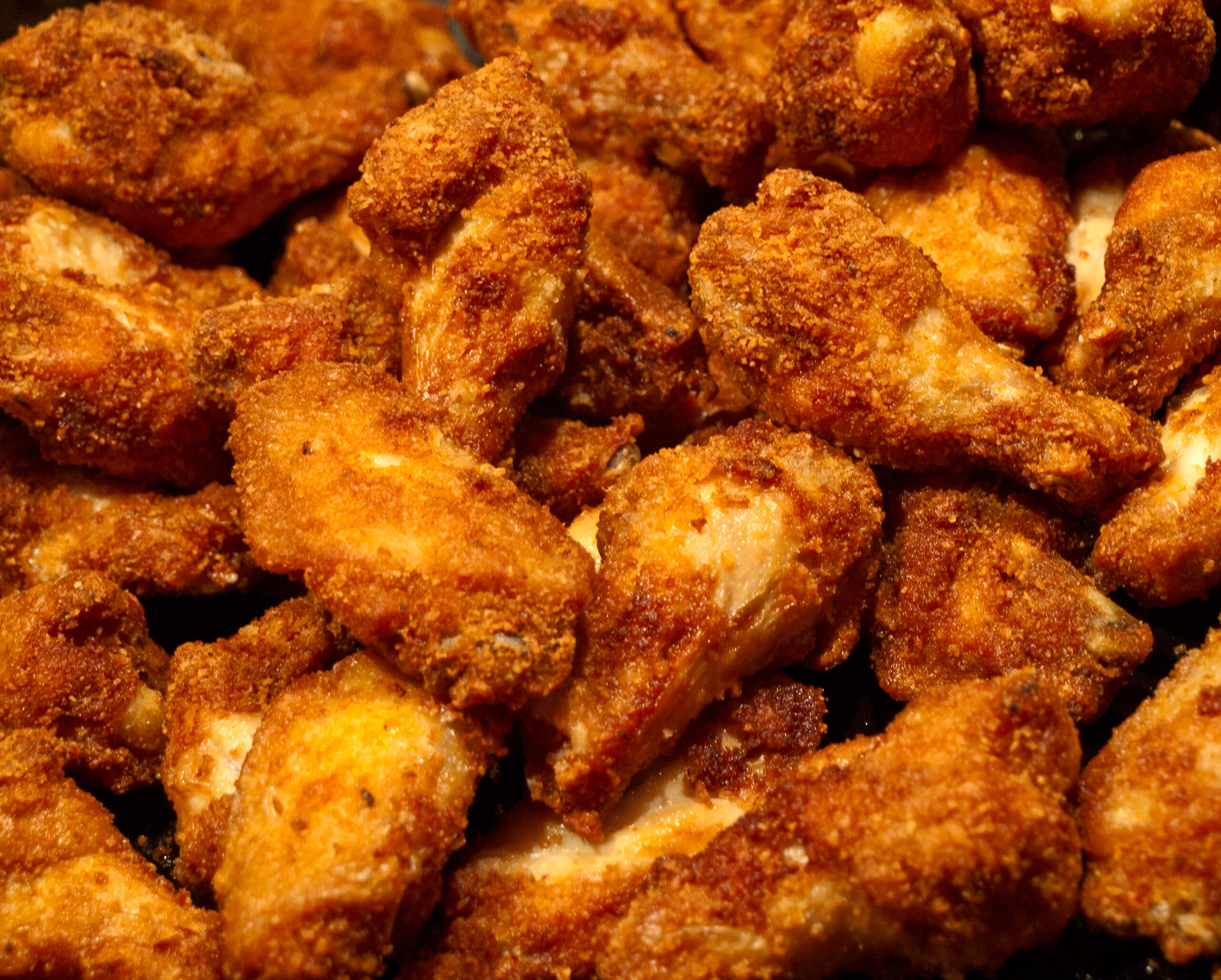 a close up of a pile of crispy fried chicken wings 