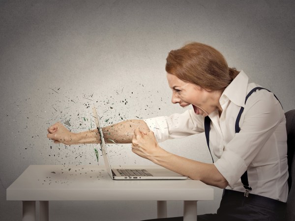 A woman punching through a laptop screen while shouting.