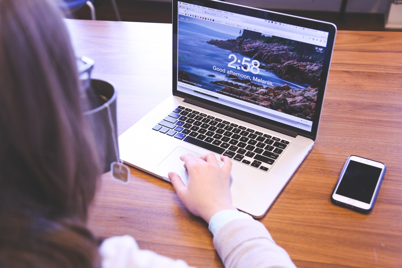 A person using a laptop computer on a wooden table.