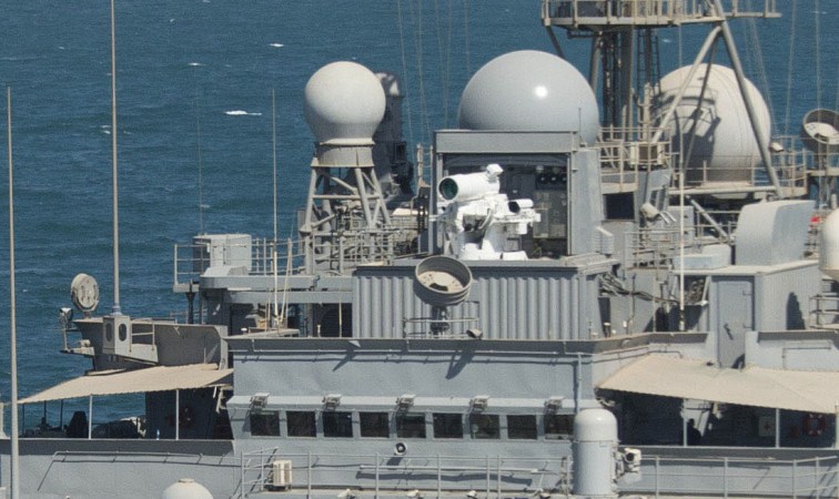 Detail of the Laser Weapon System (LaWS) on the USS Ponce. The laser gun is a white cylinder on top of a gray ship.