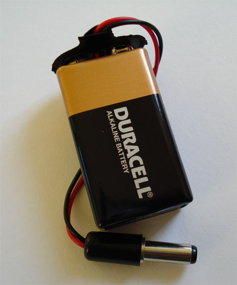 A 9-volt battery attached to a clip-on power supply.