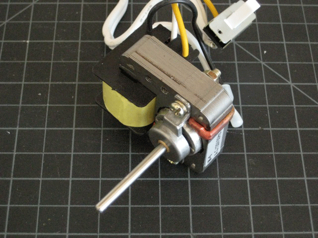 A small 120-volt AC motor on top of some black grid paper.