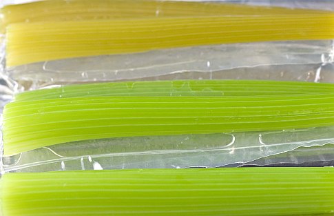 Three branches of cooked celery laid horizontally.