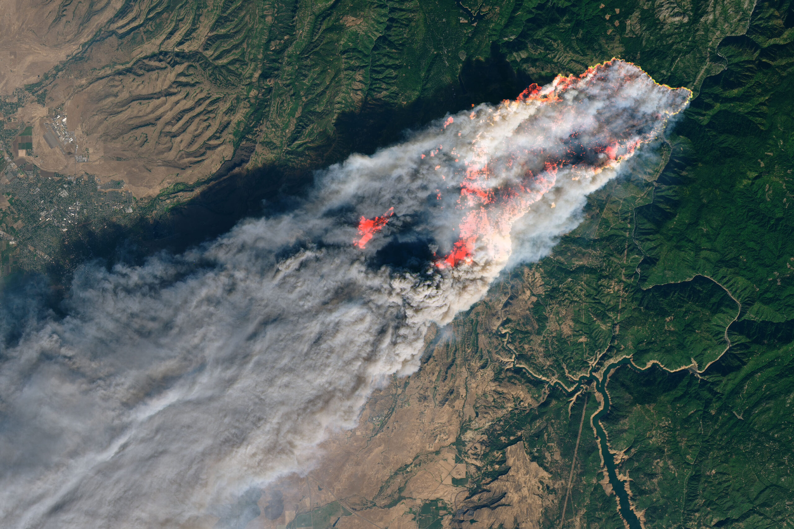 a satellite view of a massive plume of smoke and fire