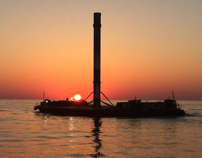 SpaceX drone ship with Falcon 9 rocket at sunset