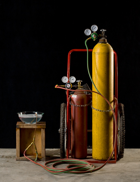 Hydrogen tanks on a cart next to a soapy bowl of water.