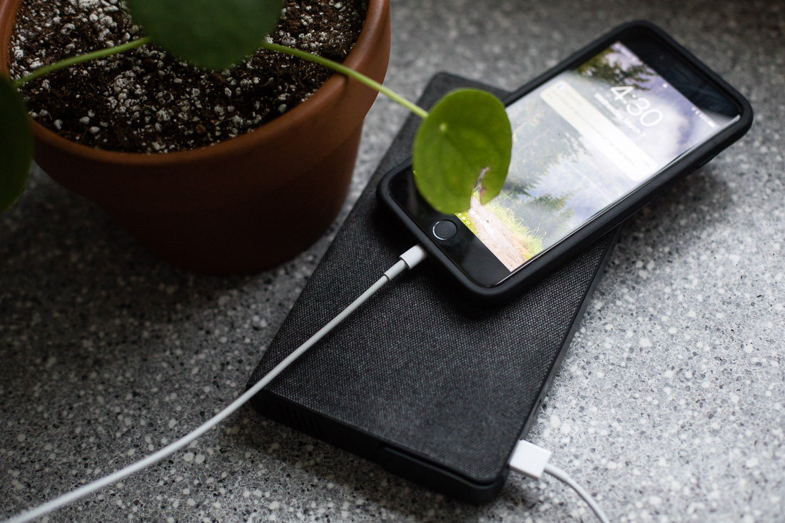 Mophie Powerstation AC charging an iPhone next to a flower pot