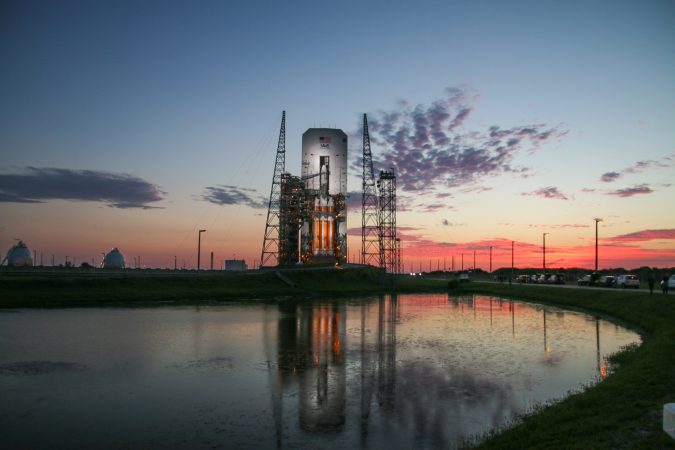 Delta IV Heavy on a launch pad with the sun setting in the background