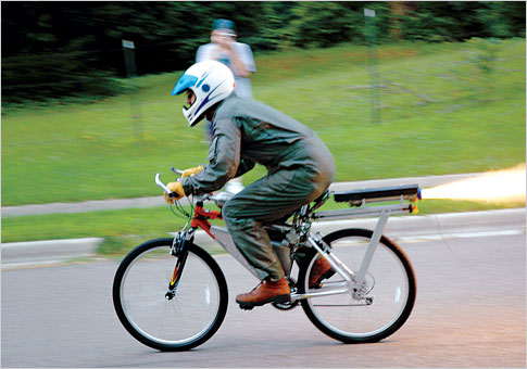 A man in a green suit riding a rocket bike.