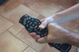 One person holding a TV remote while another person grabs it to try to take control.