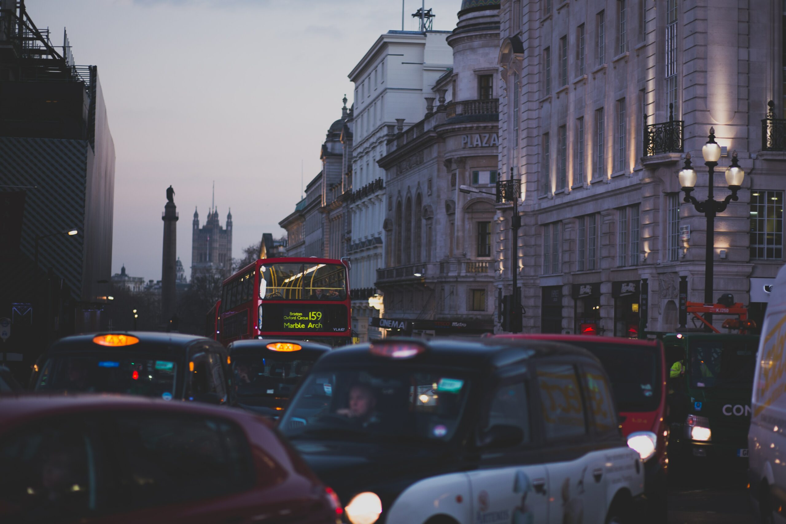 Cars and buses on busy London street at dusk.