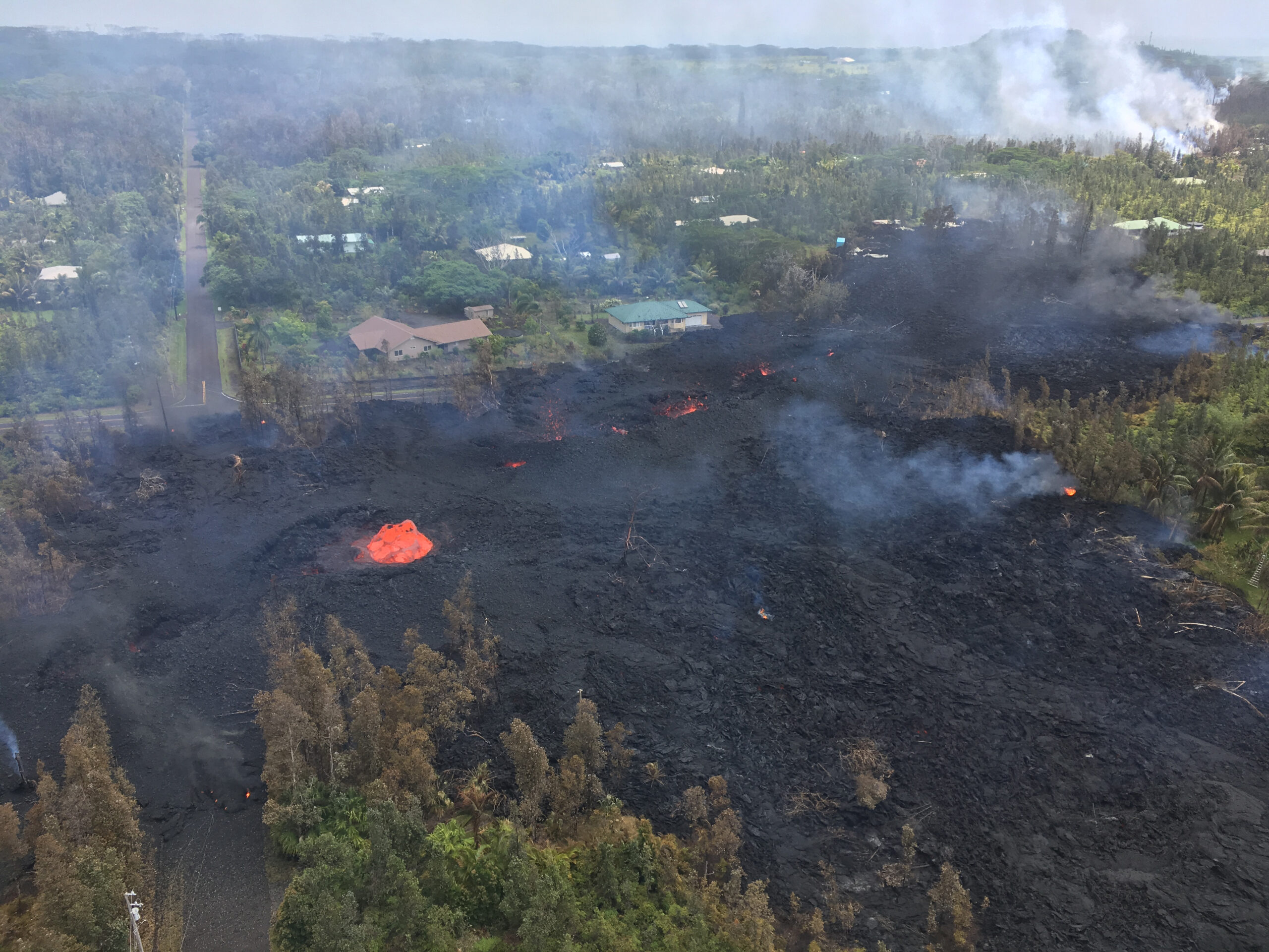 black lava steaming with an orange skylight in the middle, surrounded by forests