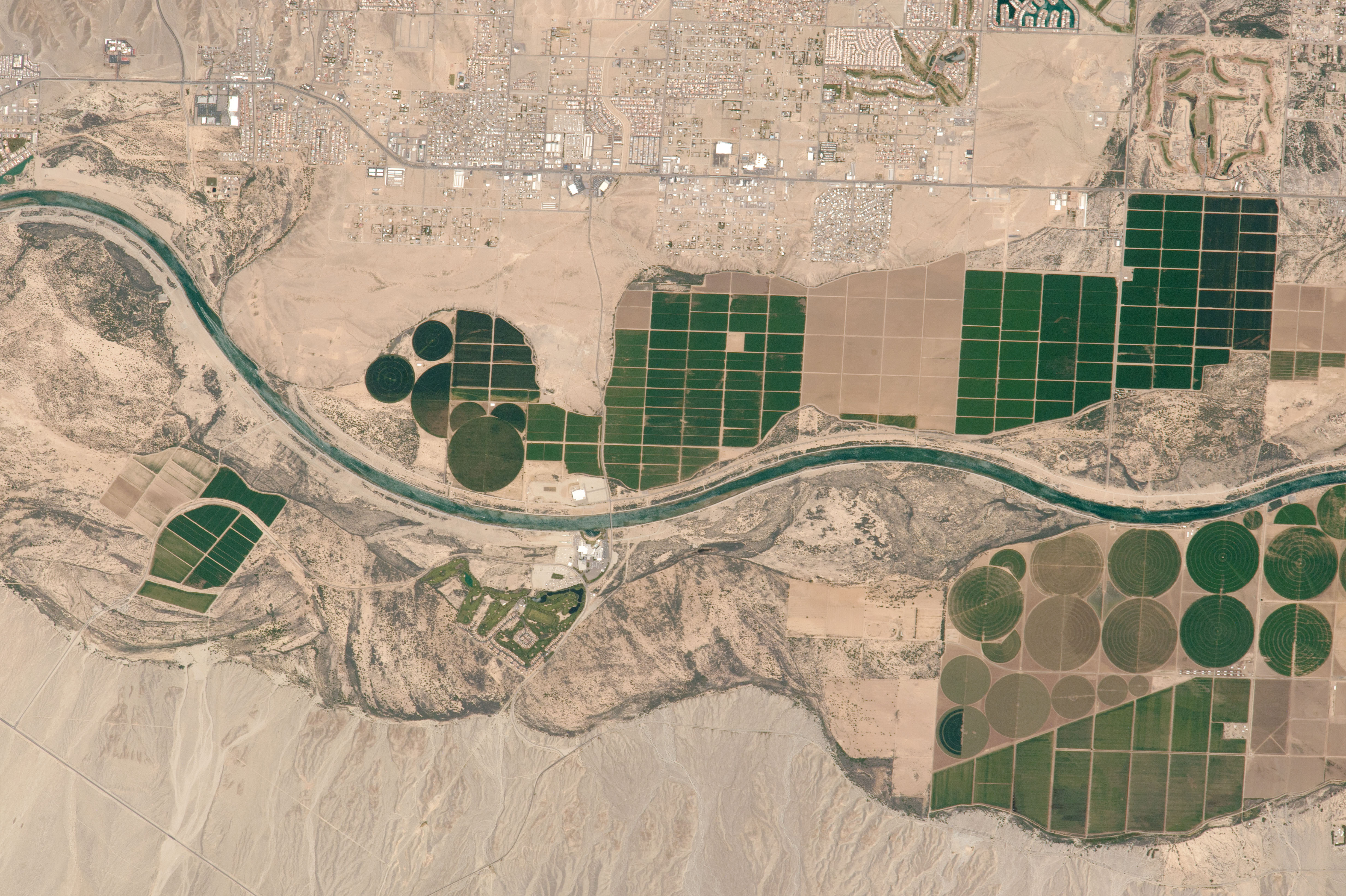 Along a stretch of the Colorado River, patches of green agriculture pop against the dry dessert.