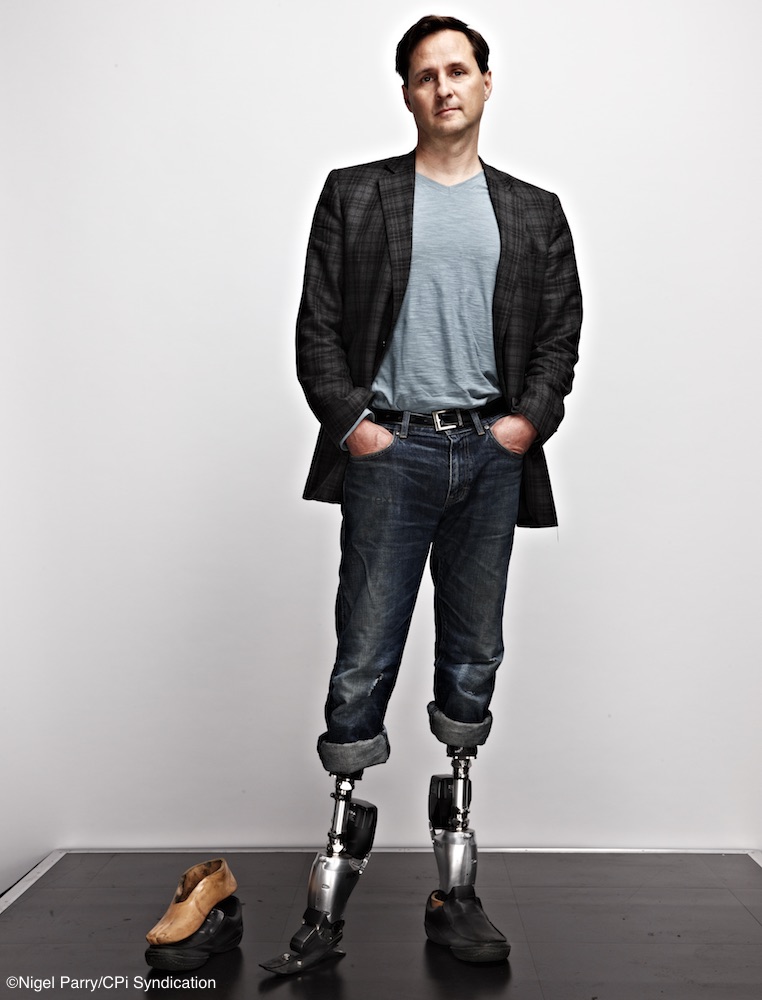 Hugh Herr posing in a suit with prosthetic legs