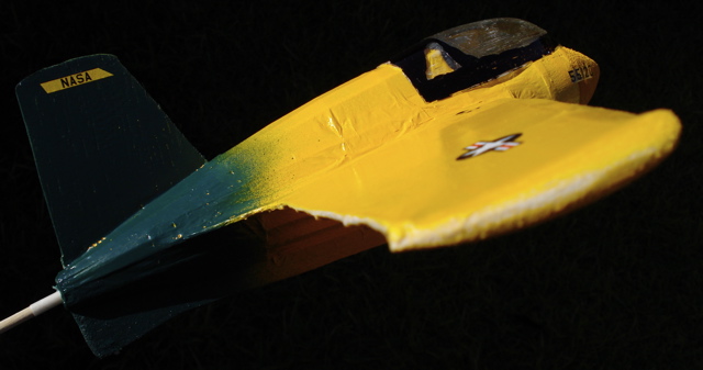 A yellow-and-green model plane against a black background.