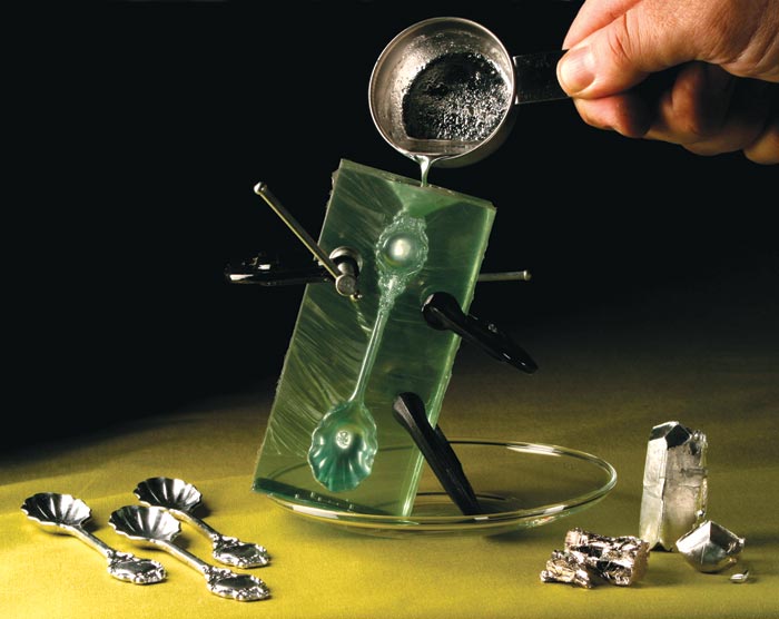 A person pouring an indium alloy into a spoon mold.