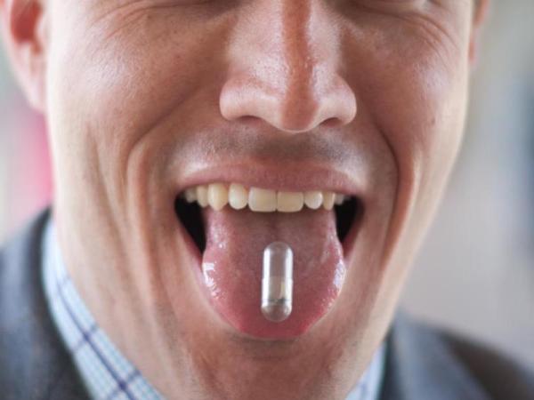 Christopher Bettinger displaying an edible battery made with melanin and dissolvable materials on his tongue.