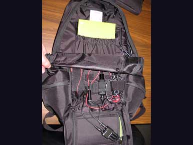 A black backpack with a chartreuse power bank and wires inside.