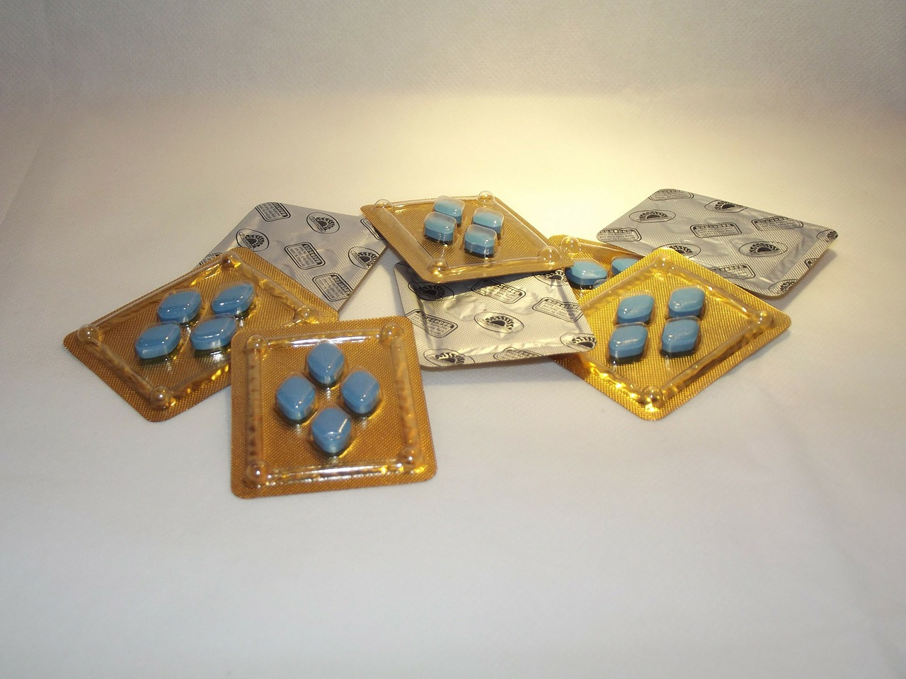 Eight packets of blue, diamond-shaped viagra pills in a pile on a white surface.