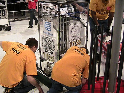 A few high school students with a homemade robot in an arena at the 2009 FIRST Robotics Competition in New York City.