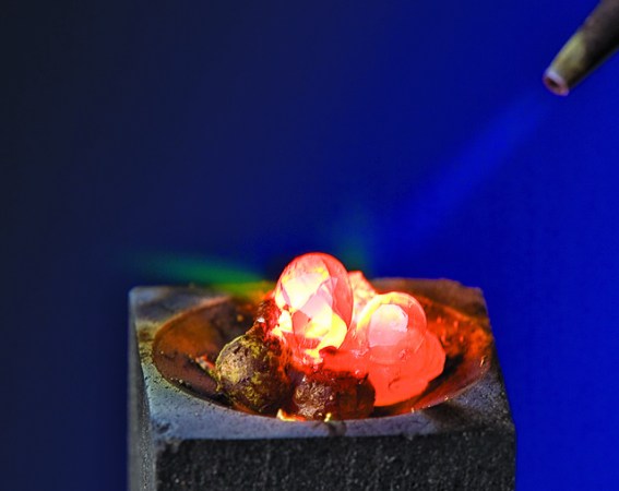 A person melting diamonds in a ring with a torch.