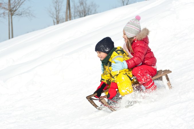 two children sledding downhill