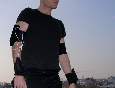 Tom Tlalim wearing all black and his W_space Wiimote suit, standing on a rooftop at dusk.