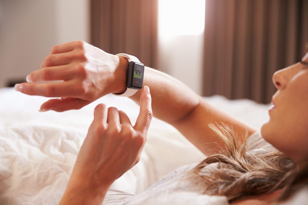 A woman using smartwatch in bed.