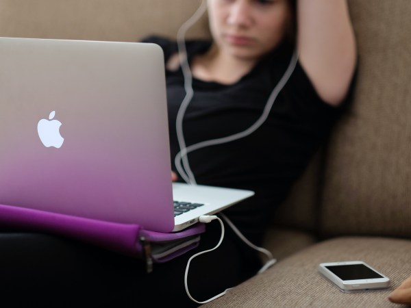 A person sitting in front of a macOS laptop looking annoyed because it decided to update at the wrong time.