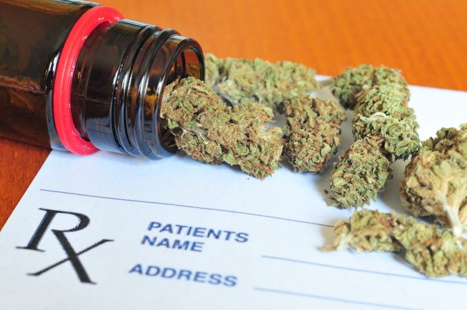 Bits of marijuana lay on a table on top of a doctor's prescription pad.