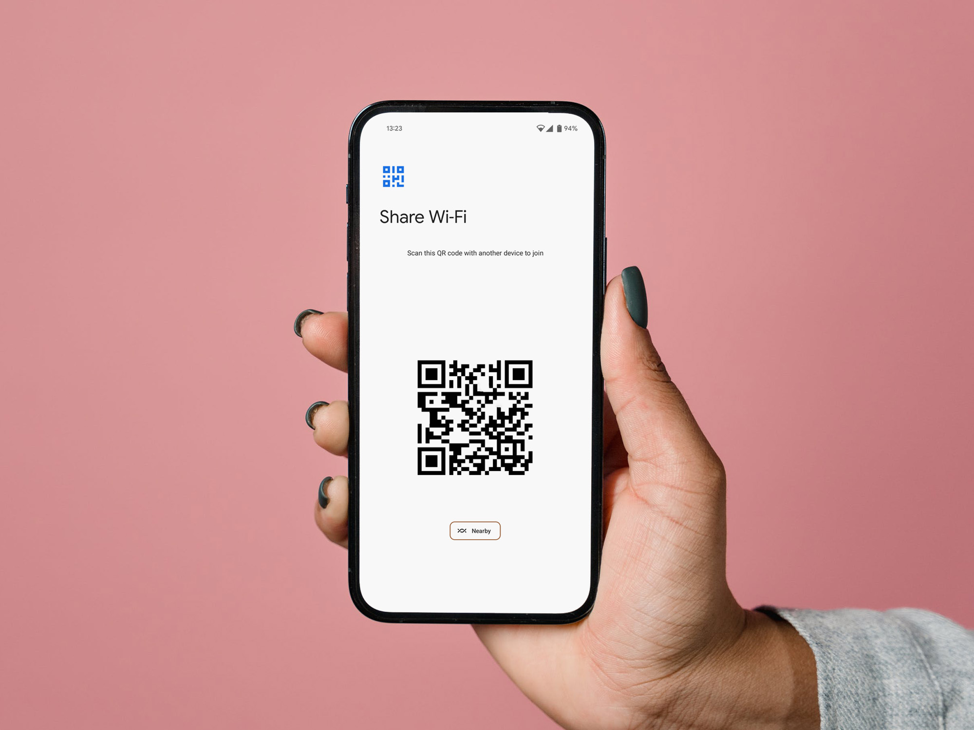 A hand holding a phone showing a QR code for sharing WiFi.