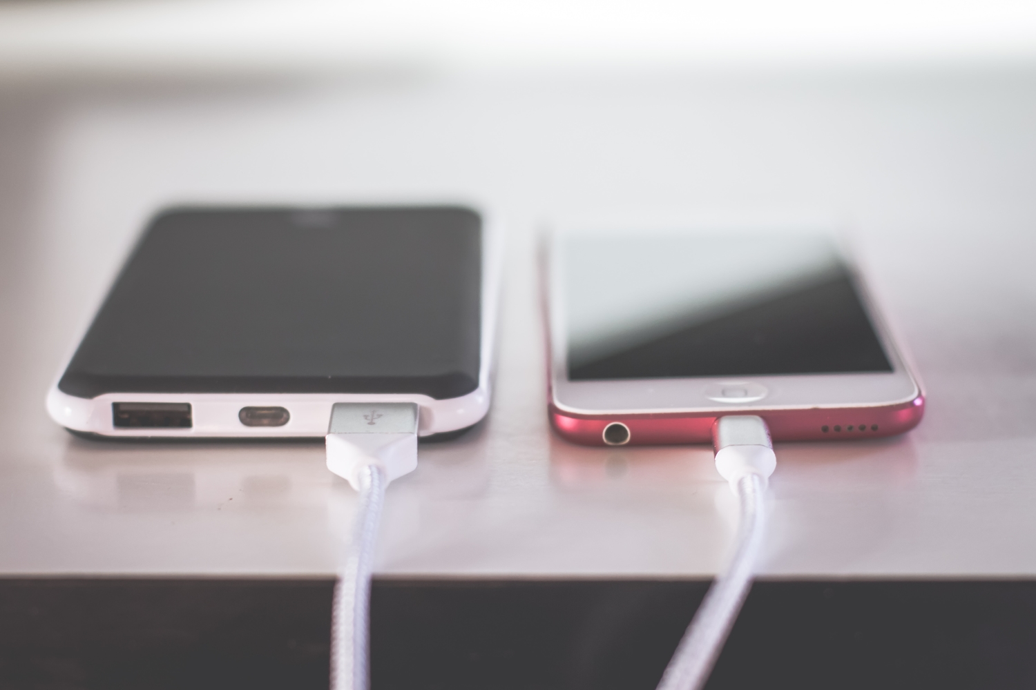 Android phone beside an iPhone charging over a table