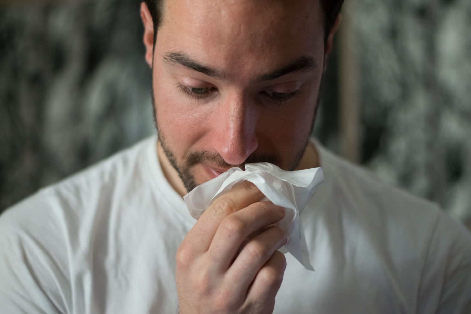 man blowing nose with tissue