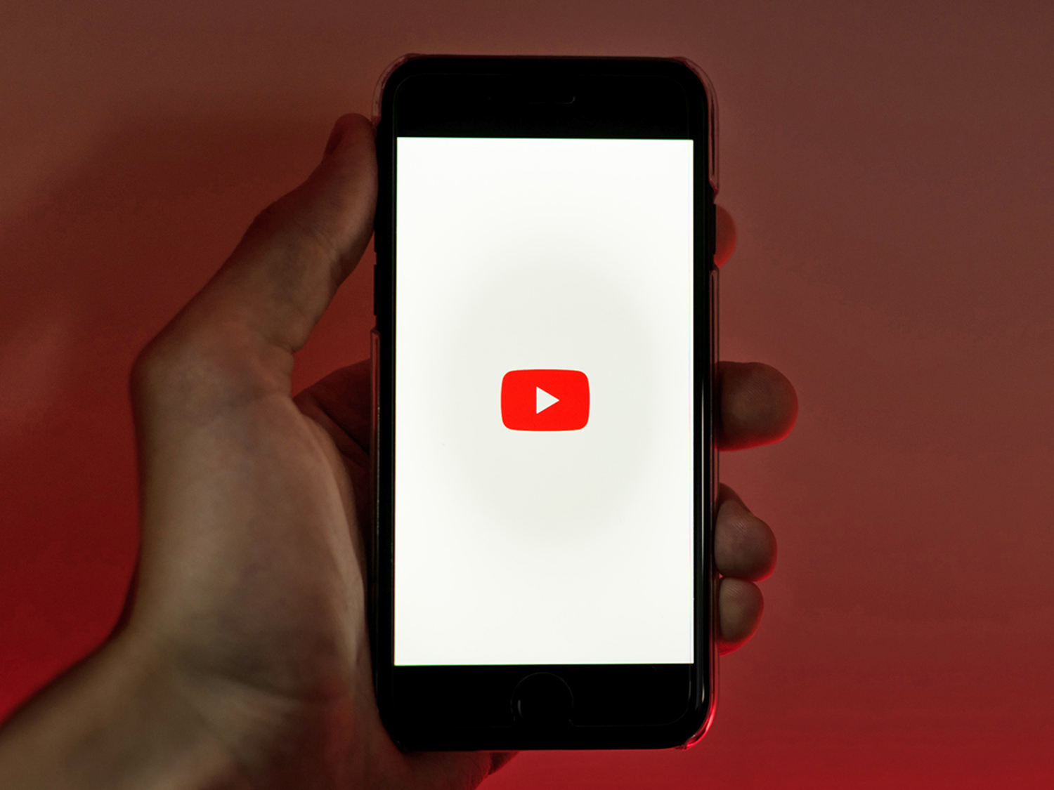Hand holding a smartphone with YouTube logo