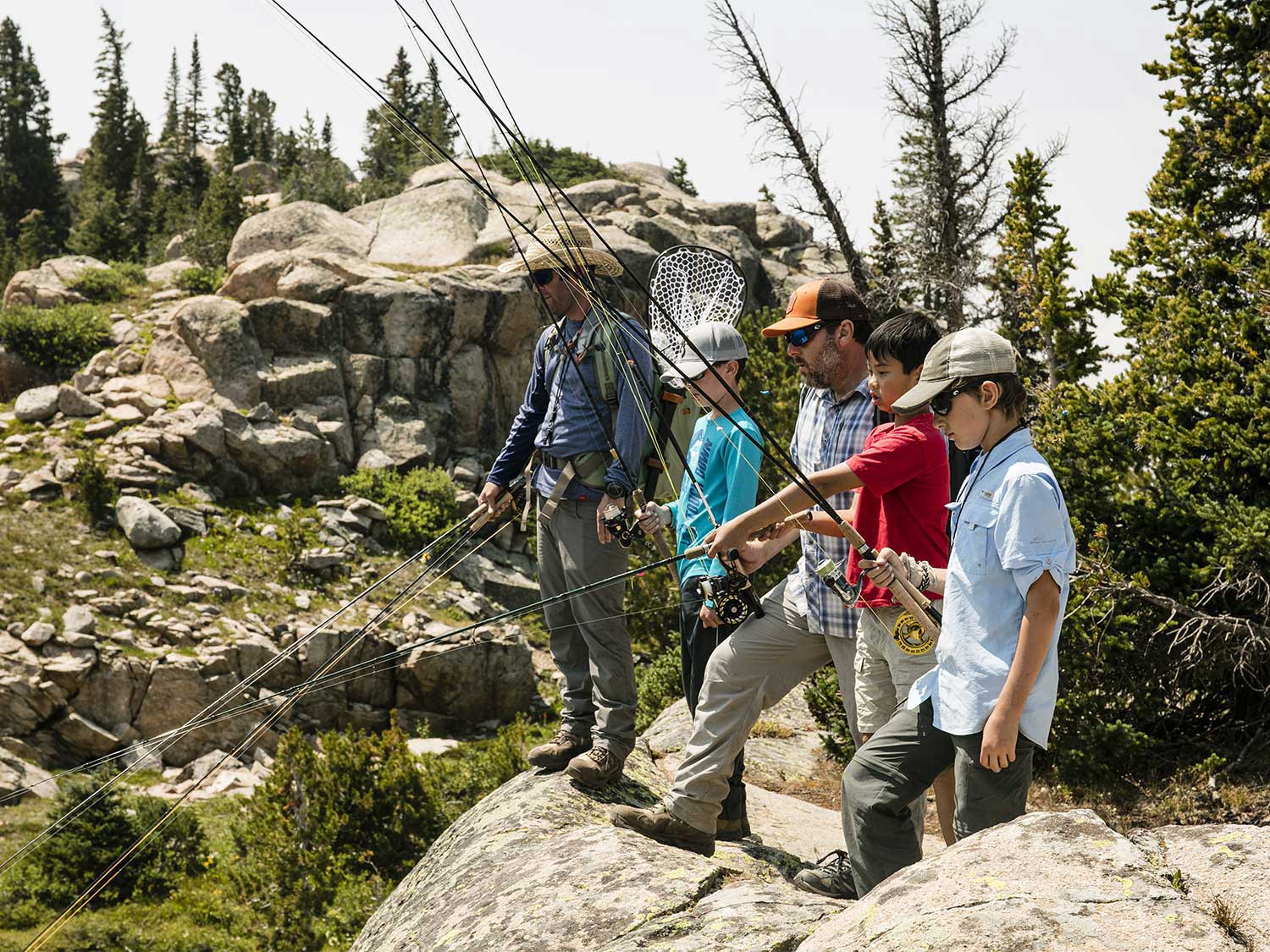 men and boys standing a rock and fishing