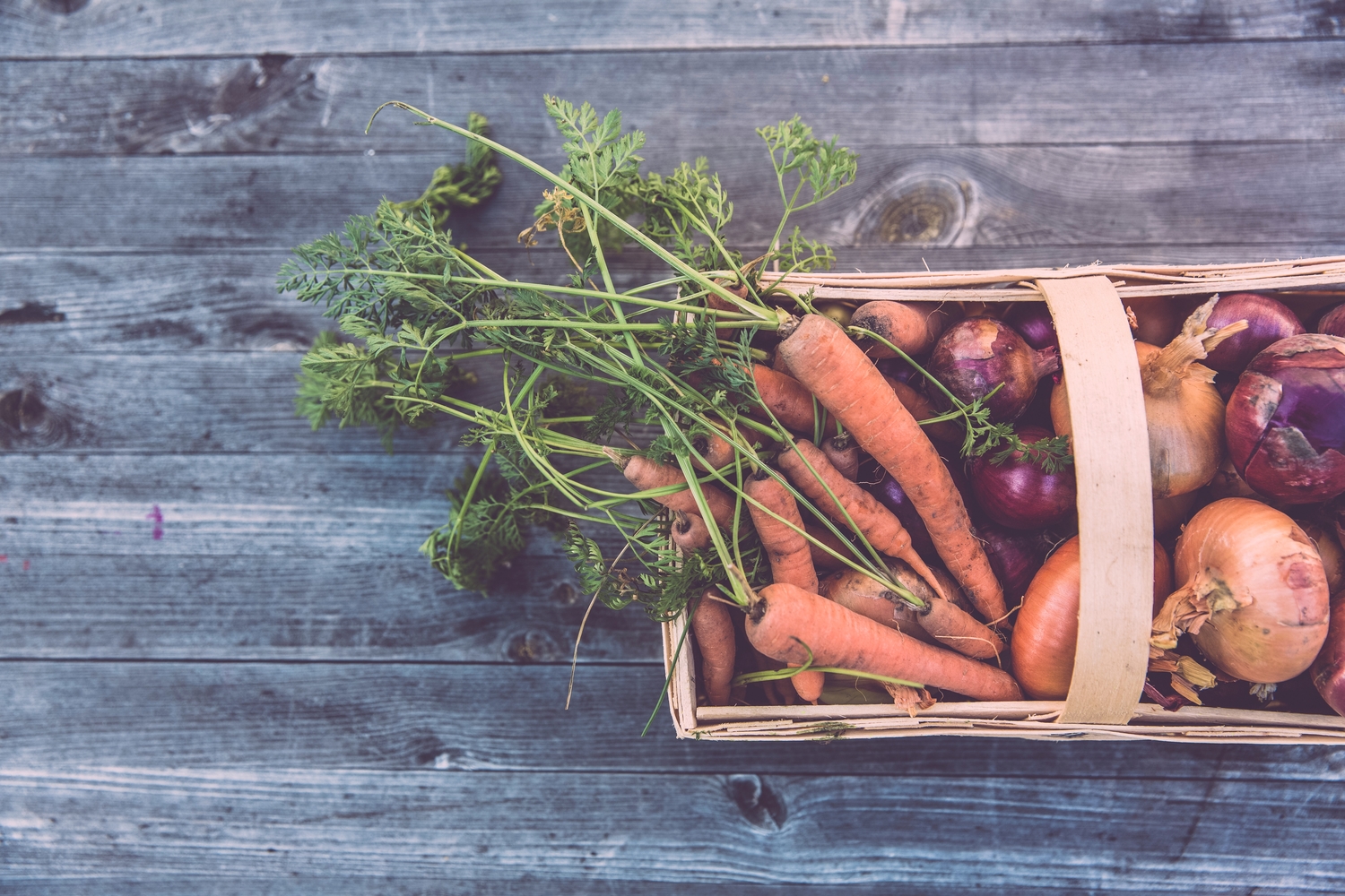 a basket of vegetables on a wooden table