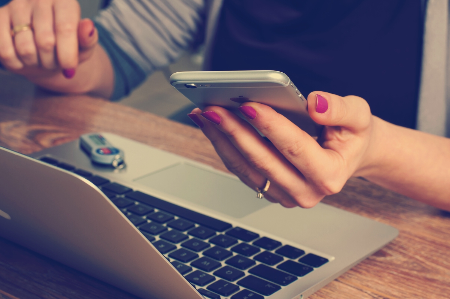 a woman using a computer and a phone with a USB device nearby